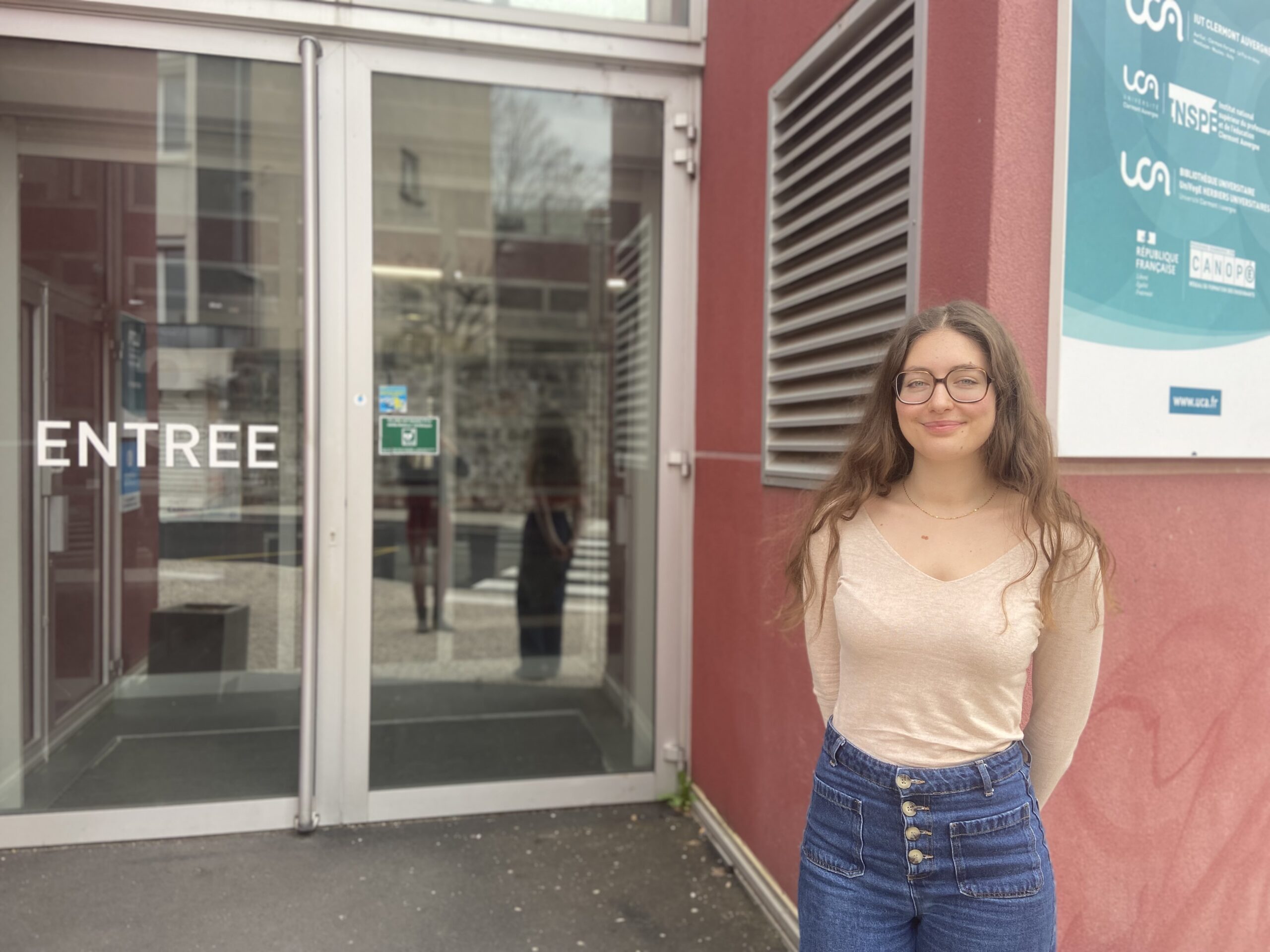 Adrianna Fanzone debout devant l'entrée principale de l'IUT du Puy-en-Velay